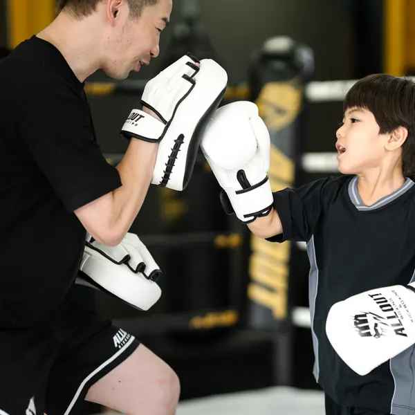 トレーナーのミットを打つ男の子