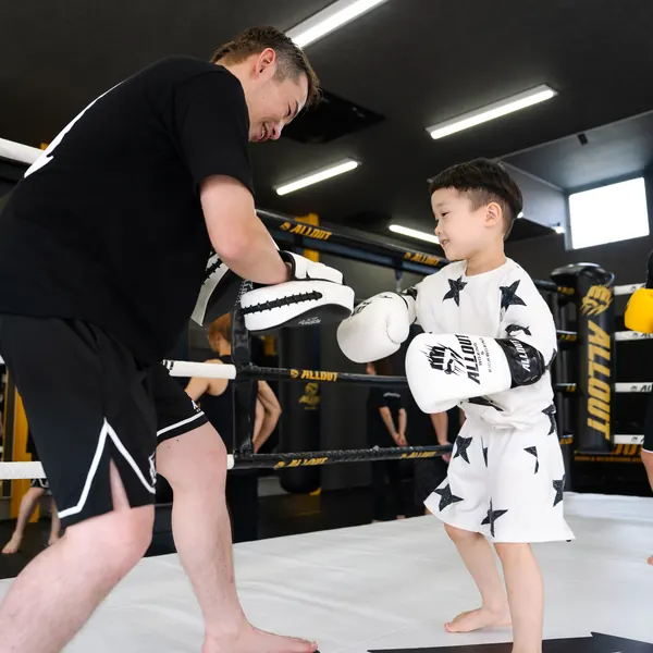 トレーナーとミット打ちをする男の子